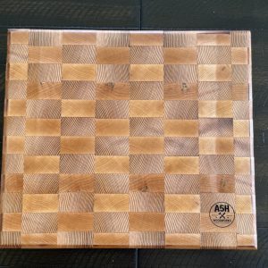 Handcrafted end-grain cutting board featuring a light maple and warm cedar checkered design.